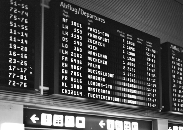 Vintage black and white airport departure board showing flights to Paris, Frankfurt, London and Amsterdam