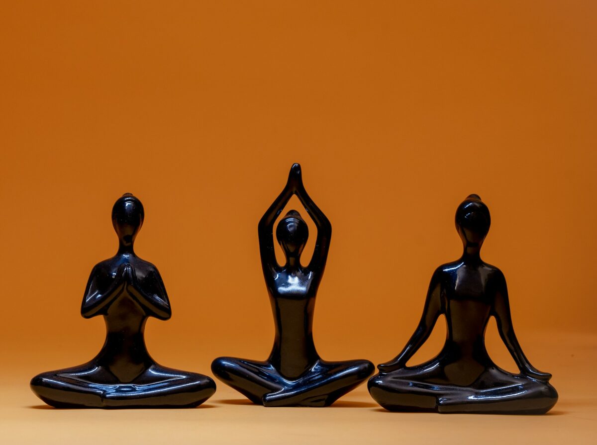 Three meditating human figures forming a triad, symbolizing the meaning of number 3 and balance in spirituality
