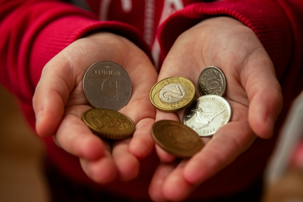 Cupped hands holding various international coins, illustrating the global superstition that an itchy palm brings incoming wealth.